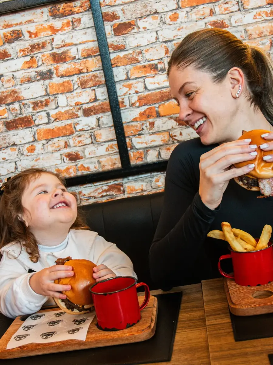 Mãe e filha rindo juntas na mesa da Comodoro
